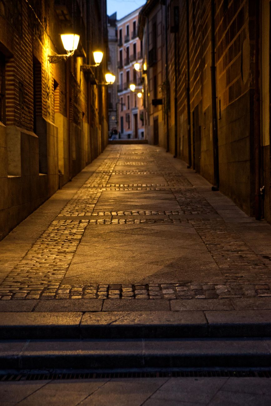 Old European cobblestone street with warm lanterns